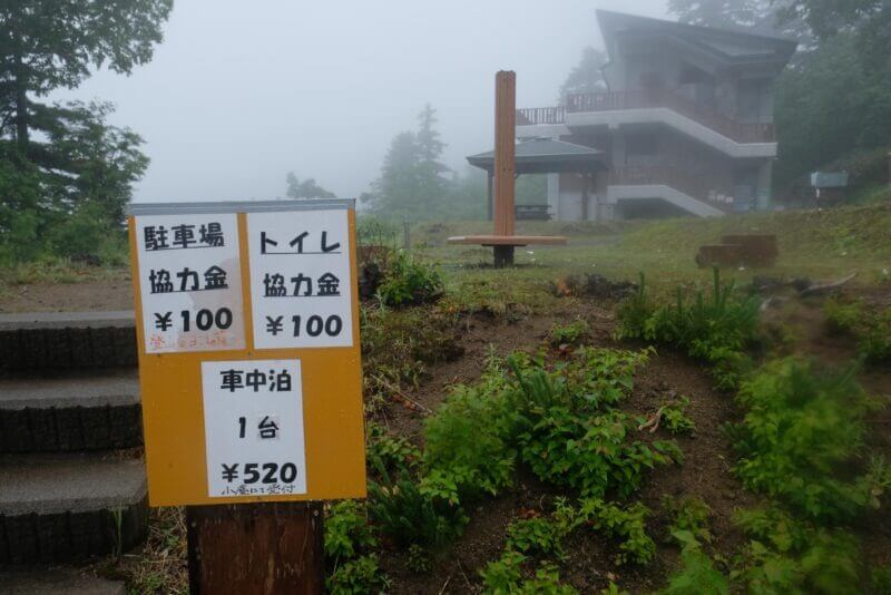 駐車場の協力金100円、トイレ協力金100円、車中泊520円と記された黄色の案内看板。