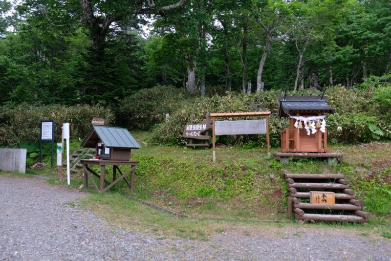 斜里岳登山口の全景。案内所、登山者名簿の小屋、そして安全を祈願する小さなお社が並んでいる。