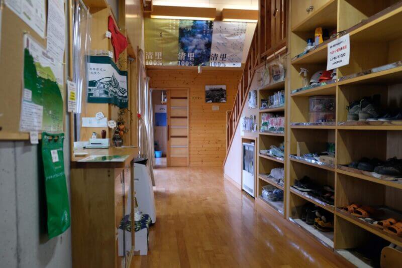 清岳荘の館内廊下。登山靴の棚と百名山の案内、清里町のポスターが見える。