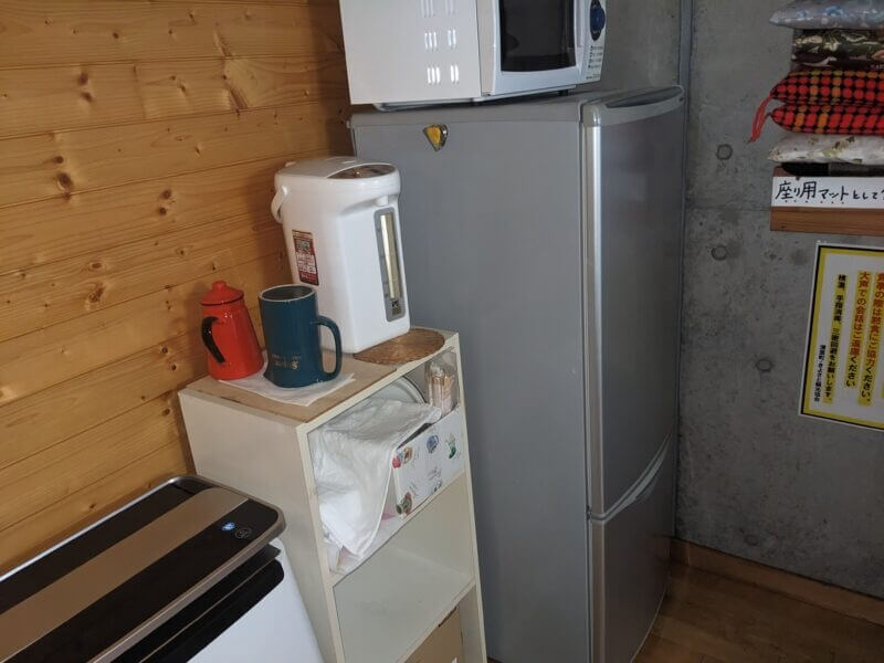冷蔵庫の横に置かれた電子レンジ、電気ポット、赤いケトルの様子。