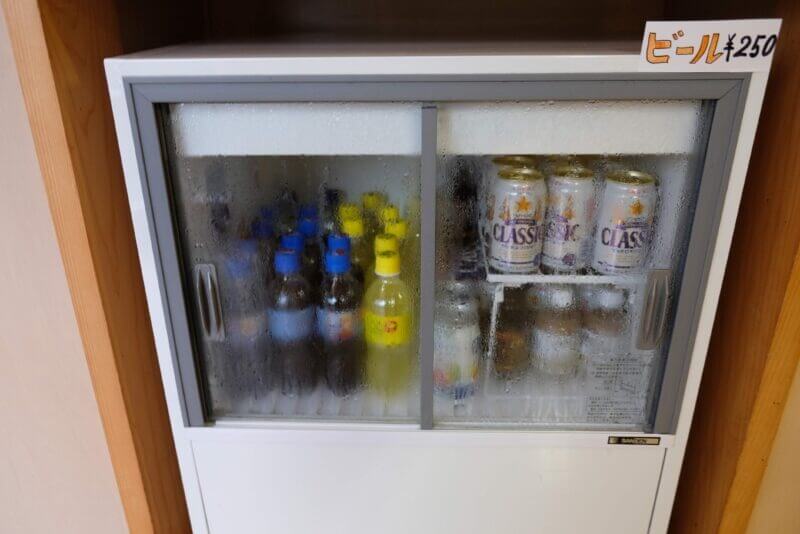 結露した冷蔵ショーケースの中にあるサッポロクラシックの缶ビール。