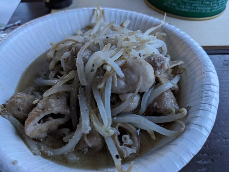 白い紙皿に盛られた、たっぷりのもやしと豚ホルモンの炒め物。