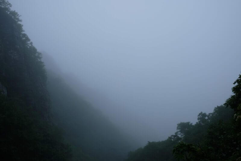 深い霧に覆われ視界が遮られた山肌の風景
