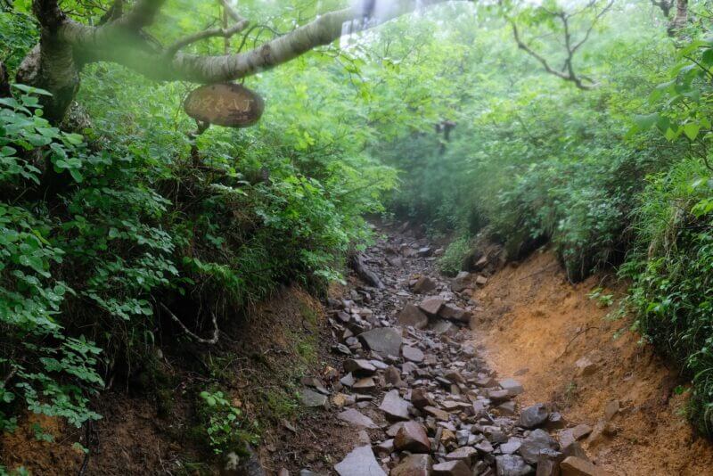 駒寄八丁と書かれた吊り看板があるガレ場の登山道