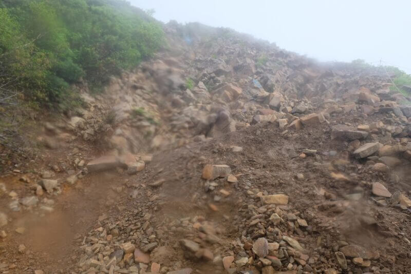 レンズの水滴で滲んだ急峻な岩ガレ場の登り