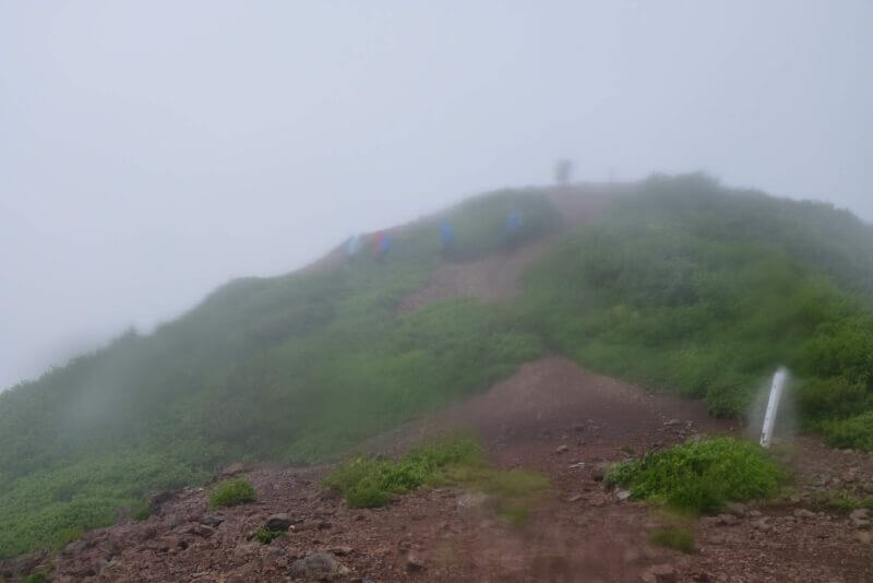 濃霧の尾根道を歩く登山者たちのシルエット