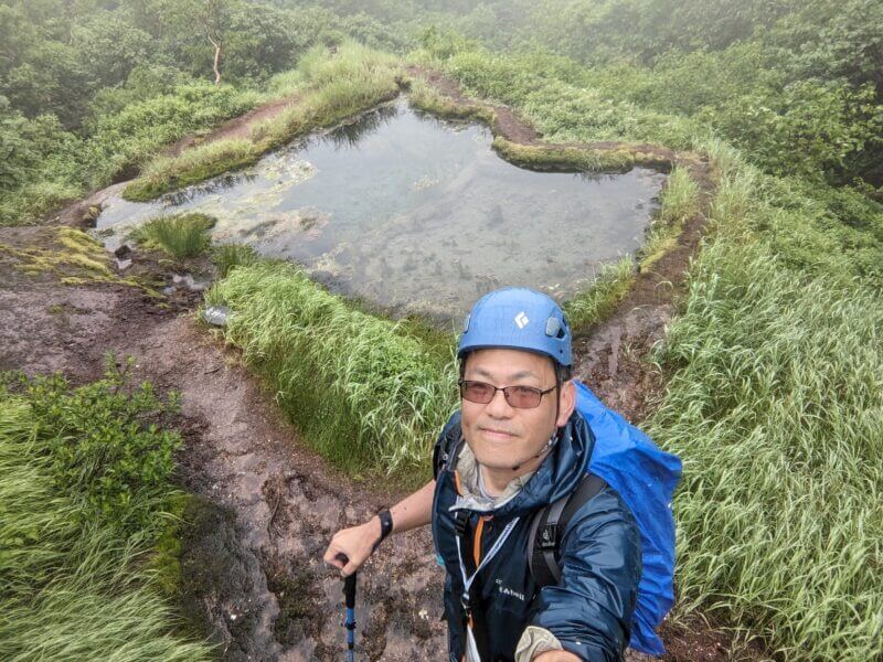 龍神の池を背景にした登山者の自撮り