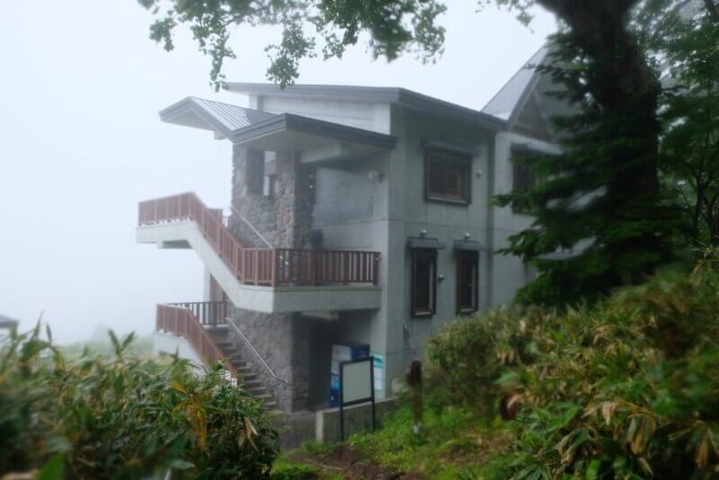 霧の中に立つコンクリート造りの近代的な山小屋
