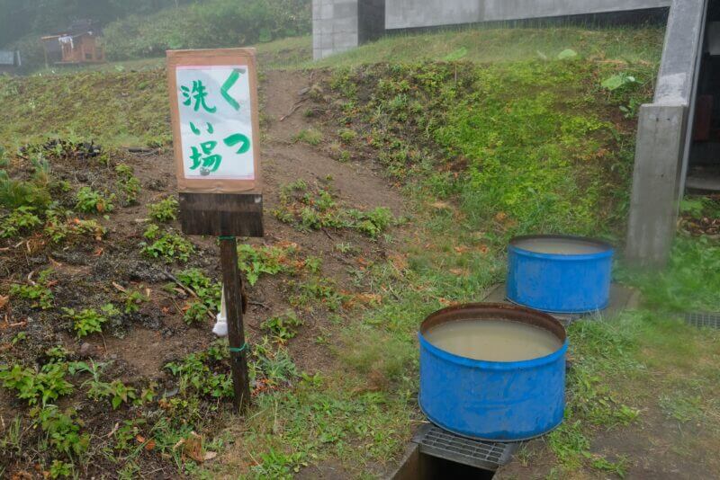 屋外に置かれた青いドラム缶の靴洗い場