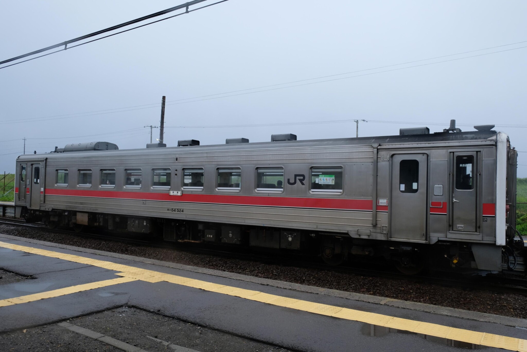 雨のJR網走駅（あるいは周辺駅）に停車する、キハ54形気動車の一両編成。