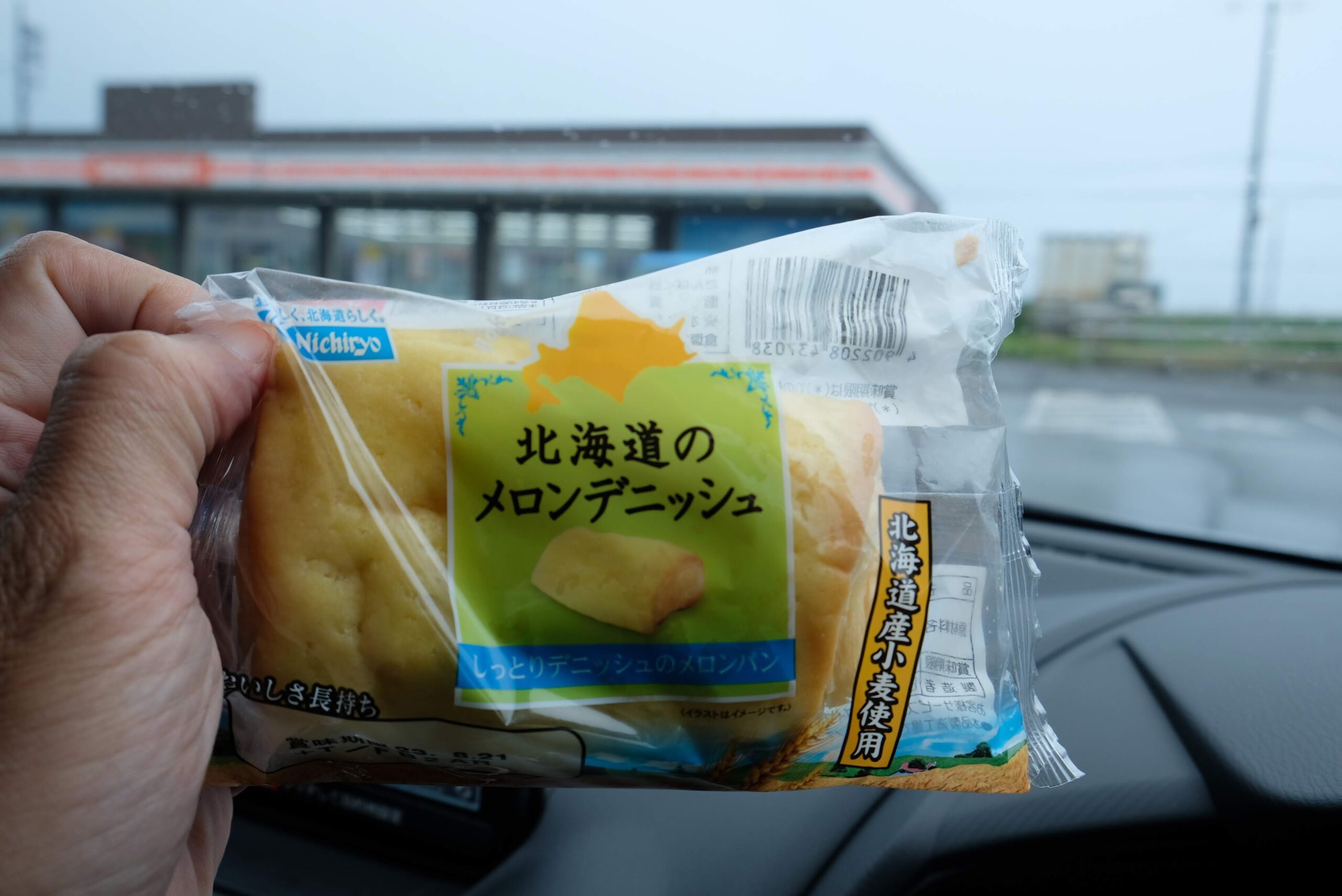 車内で日糧製パンの「北海道のメロンデニッシュ」を手に持つ様子。