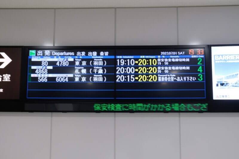 夜の空港の出発案内掲示板。19:33の時点で、羽田行きなどが20:10以降に遅延している表示。