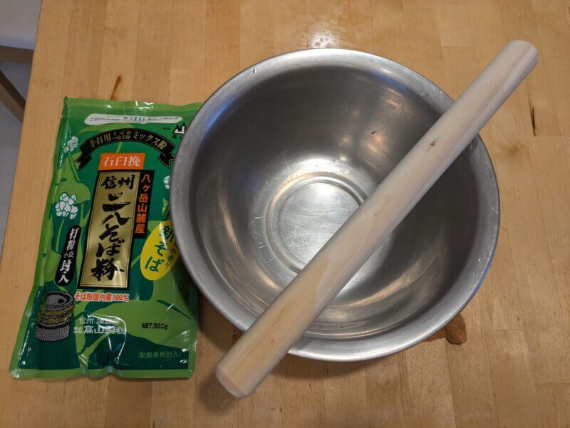 テーブルに置かれた信州二八そば粉、ステンレスボウル、木製の麺棒。