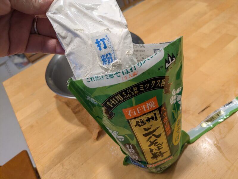 そば粉のパッケージから打粉の小袋を取り出す様子。