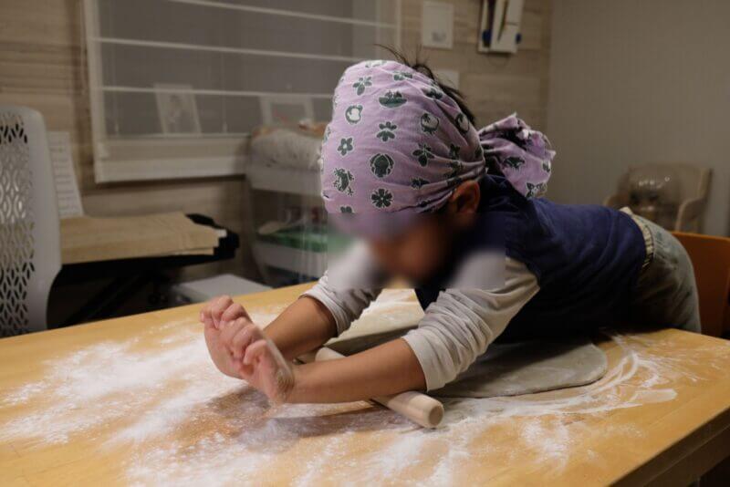 子供が麺棒を使ってそば生地を薄く伸ばす延しの工程。