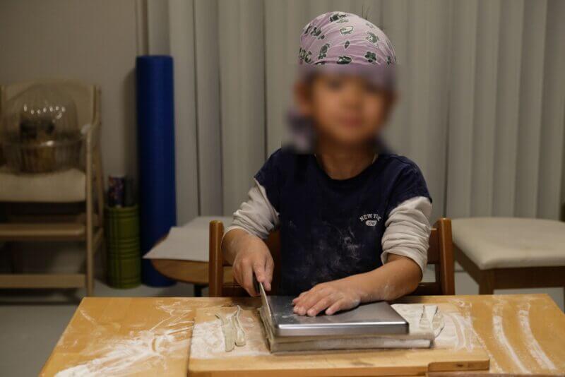 子供が駒板と包丁を使ってそばを切る工程。