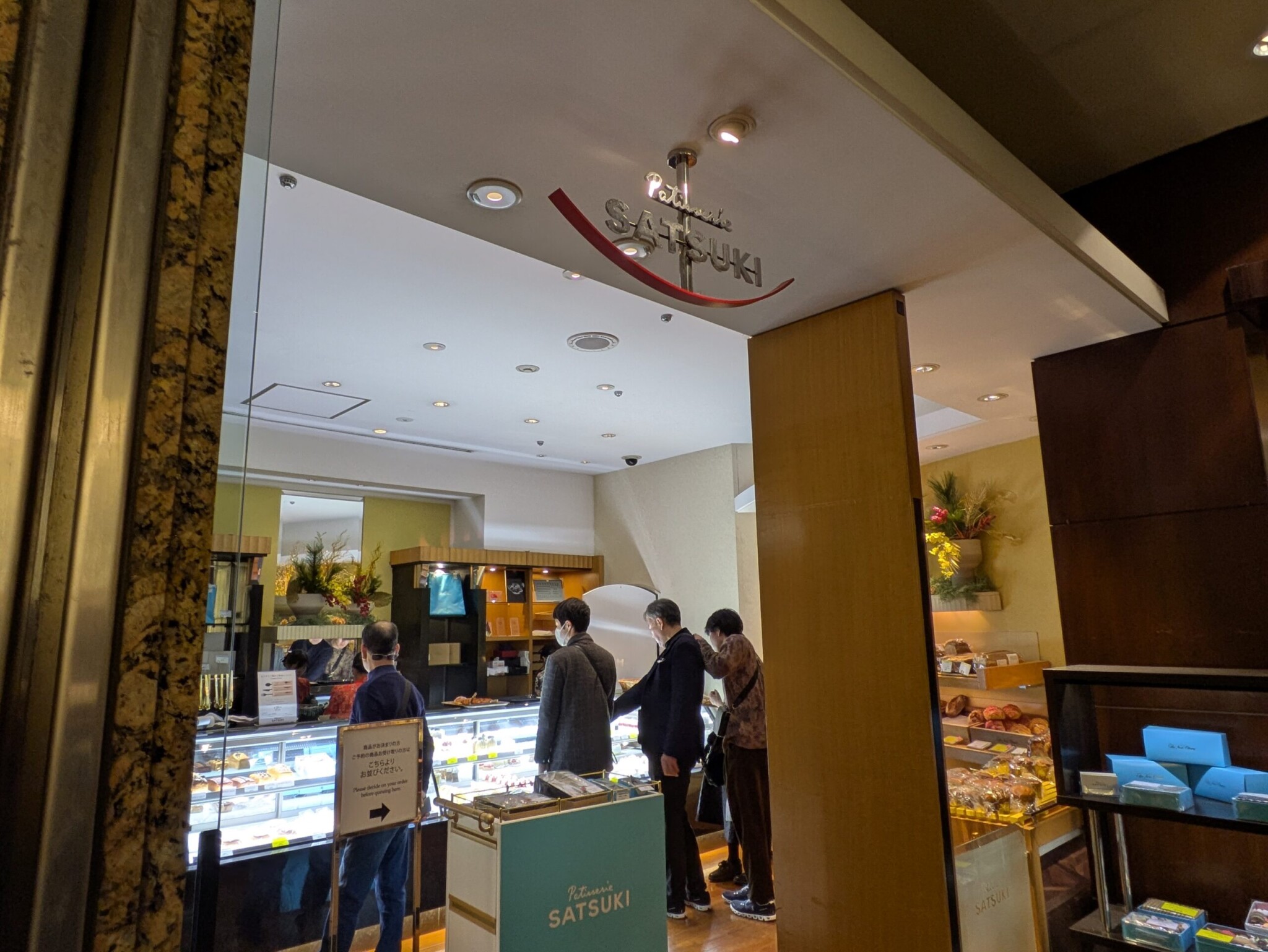 パティスリーSATSUKI de店舗入口の様子。客がショーケースを眺めている。